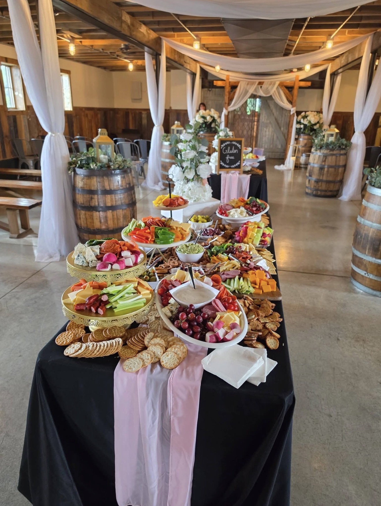 Grazing table with cake and gluten-free signage in a draped barn venue