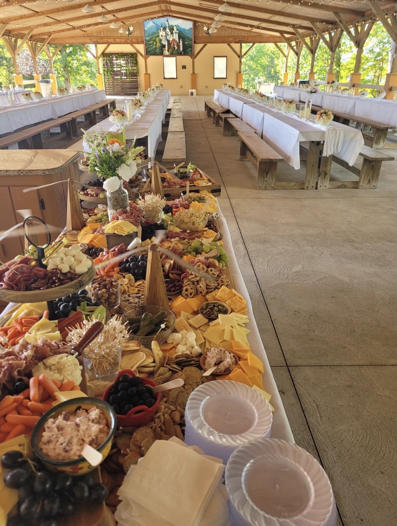 Large charcuterie spread at an open-air pavilion reception with long banquet tables